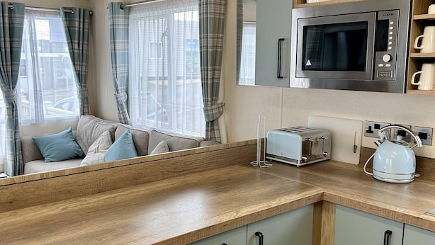 Une cuisine moderne équipée d’un four à micro-ondes, d’un grille-pain, d’une bouilloire et de meubles de rangement en bois.