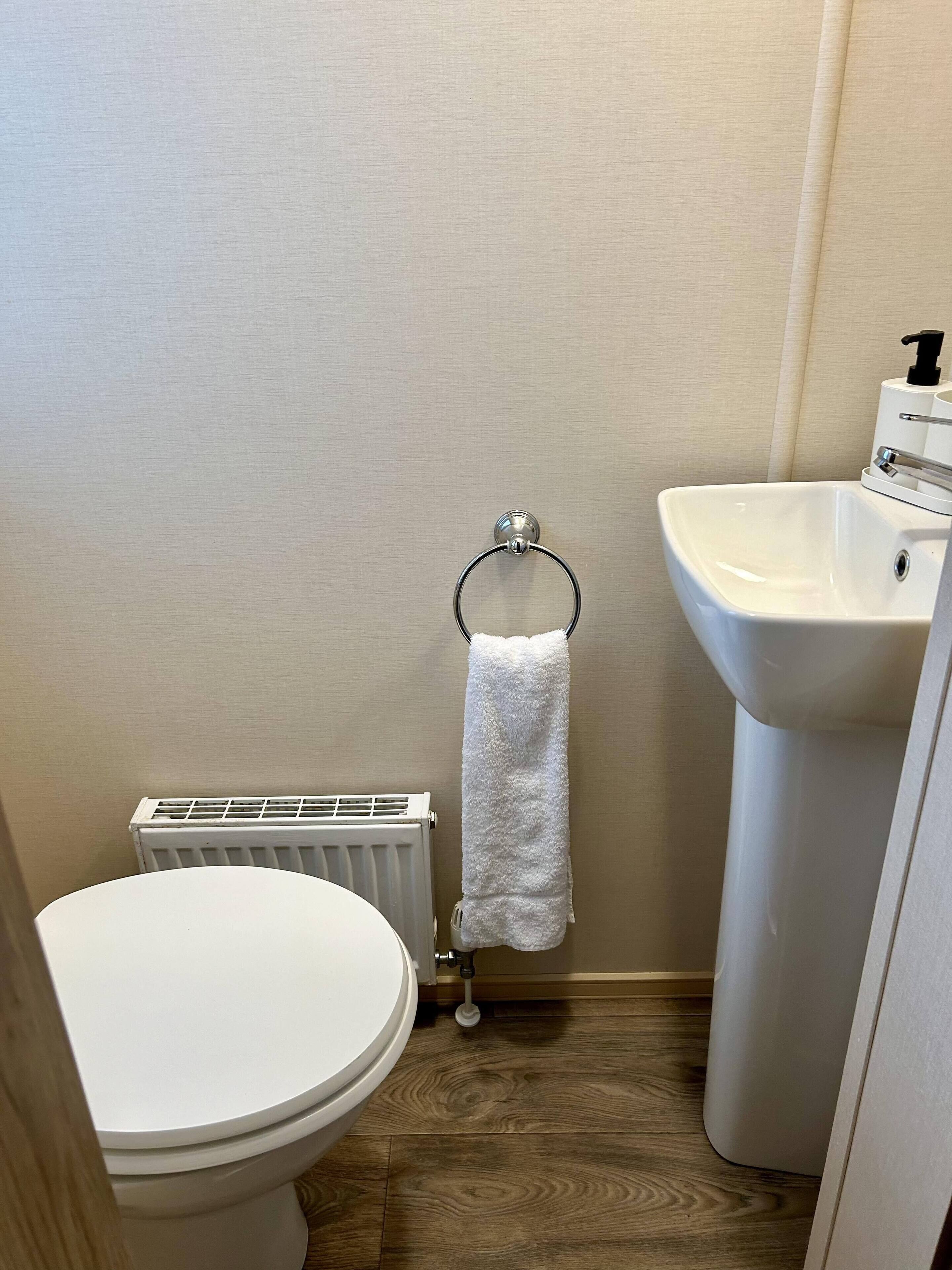 Un baño pequeño con inodoro, radiador y lavamanos.