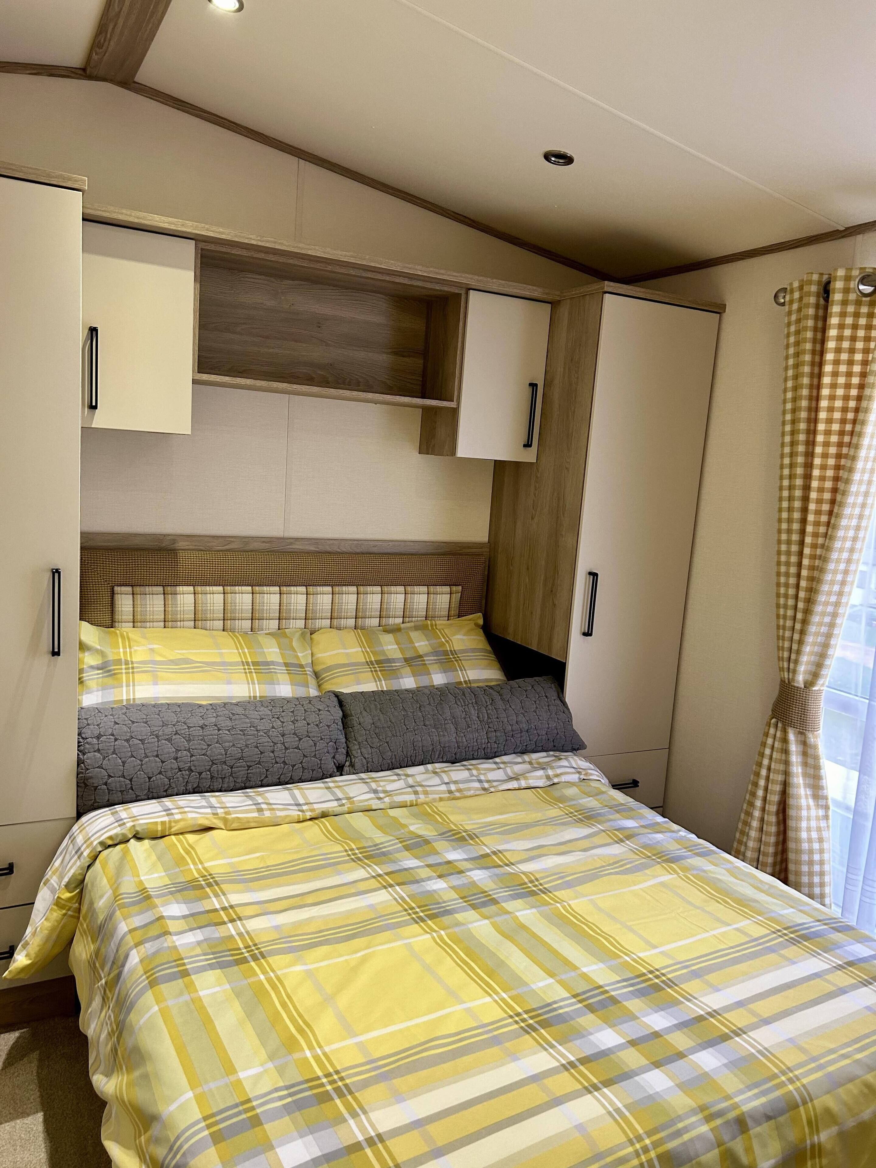 A bedroom with a bed, a wardrobe, and a window with curtains.
