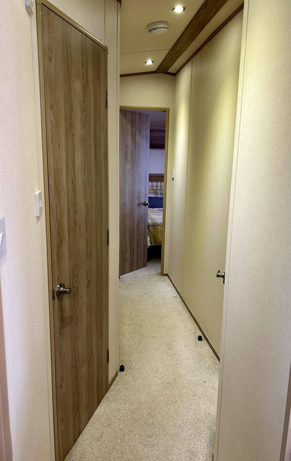 A narrow hallway with wooden doors and a carpeted floor.