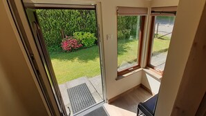 Quarto com porta de correr de vidro que dá para um jardim, uma janela pequena e uma porta.