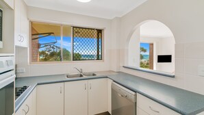 A modern kitchen with a built-in dishwasher, a double sink, and a window with a view of the beach. - Pacific Gables 1 - Absolute Beachfront Tugun - Linen Provided - Min. 3 Night Stays! (Tugun)