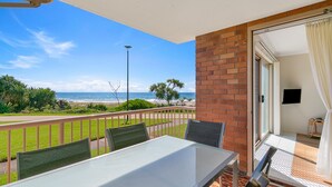 A balcony with a table and chairs, a view of the beach, and a brick wall. - Pacific Gables 1 - Absolute Beachfront Tugun - Linen Provided - Min. 3 Night Stays! (Tugun)