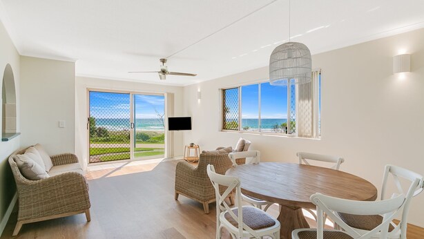 A spacious room with a large dining table, wicker chairs, and a ceiling fan. - Pacific Gables 1 - Absolute Beachfront Tugun - Linen Provided - Min. 3 Night Stays! (Tugun)