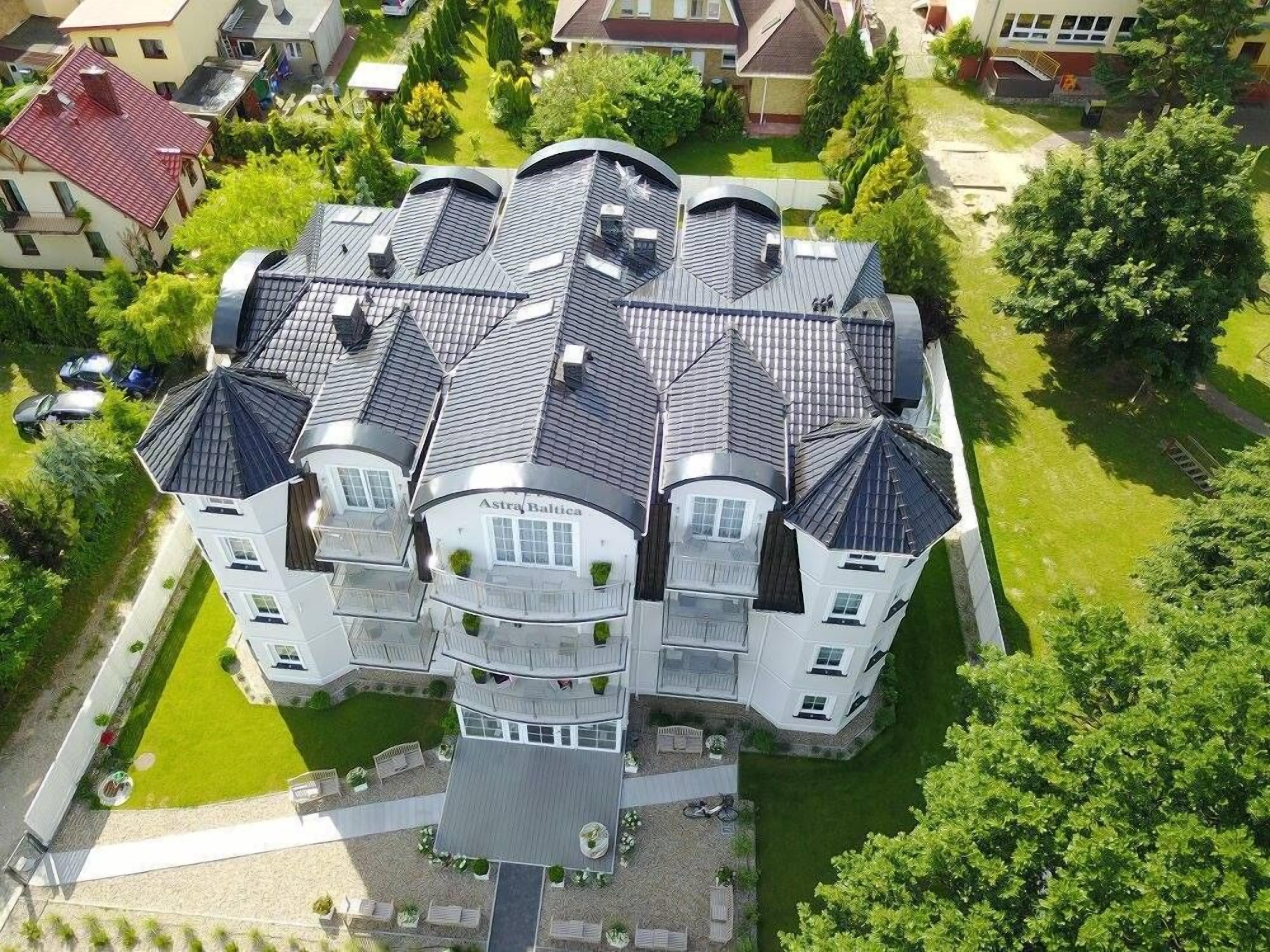 Ein großes, mehrstöckiges Haus mit symmetrischer Gestaltung, das mehrere Balkone und einen zentralen Innenhof aufweist.