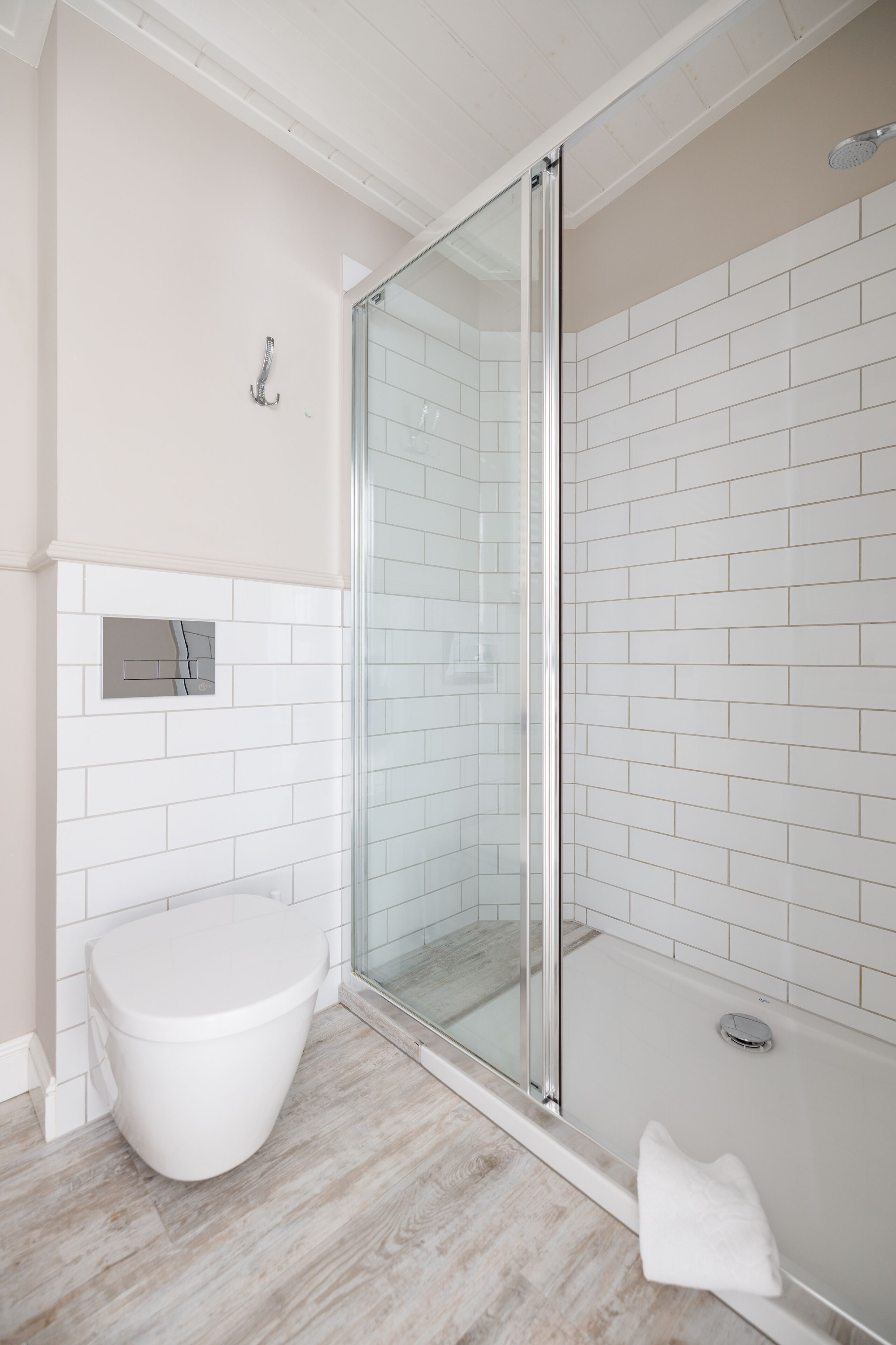 Un baño moderno con cabina de ducha de vidrio, inodoro y bañera, ambos blancos.