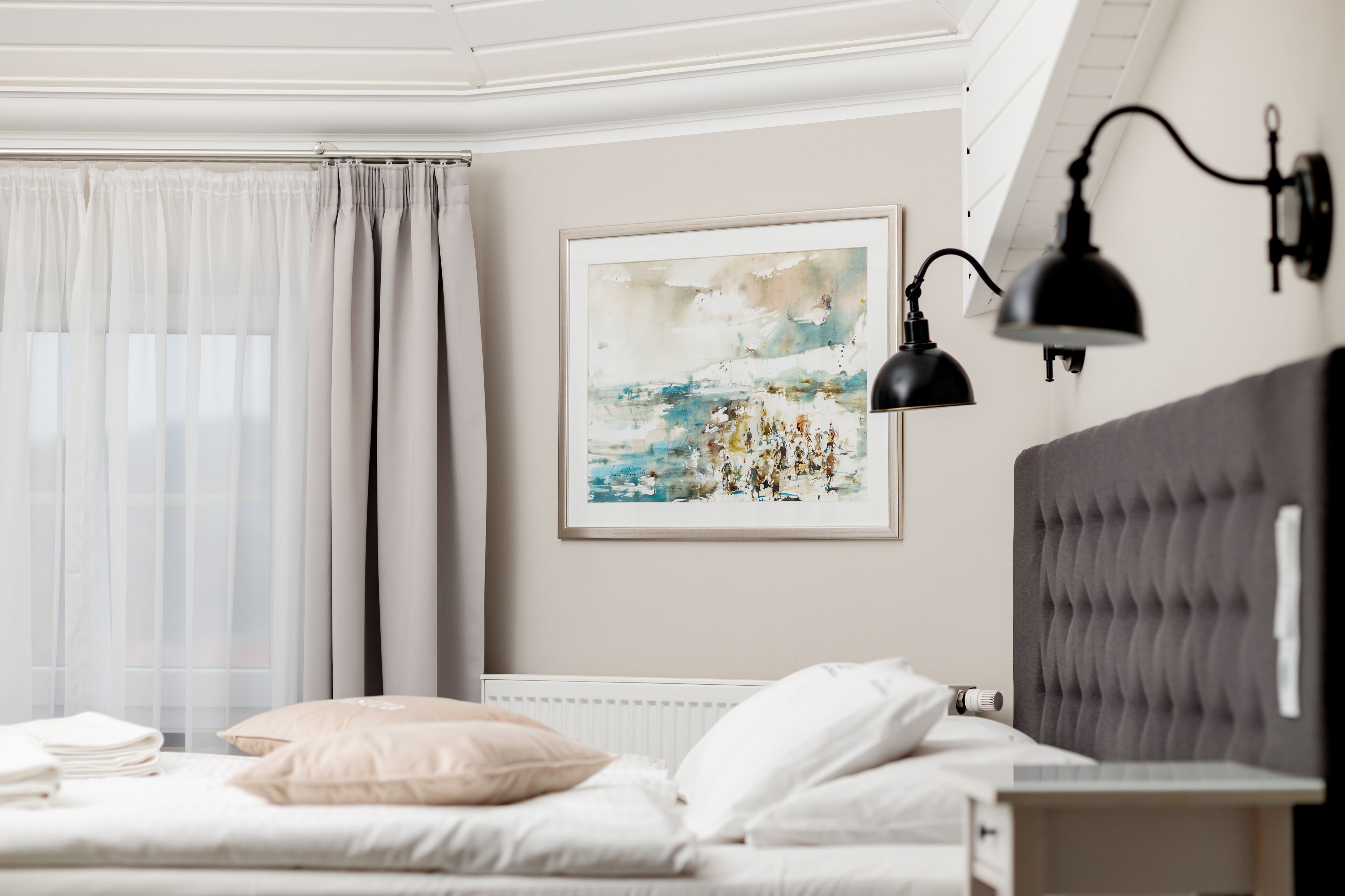A bedroom with a bed, a headboard, a bedside table, a lamp, and a painting on the wall.