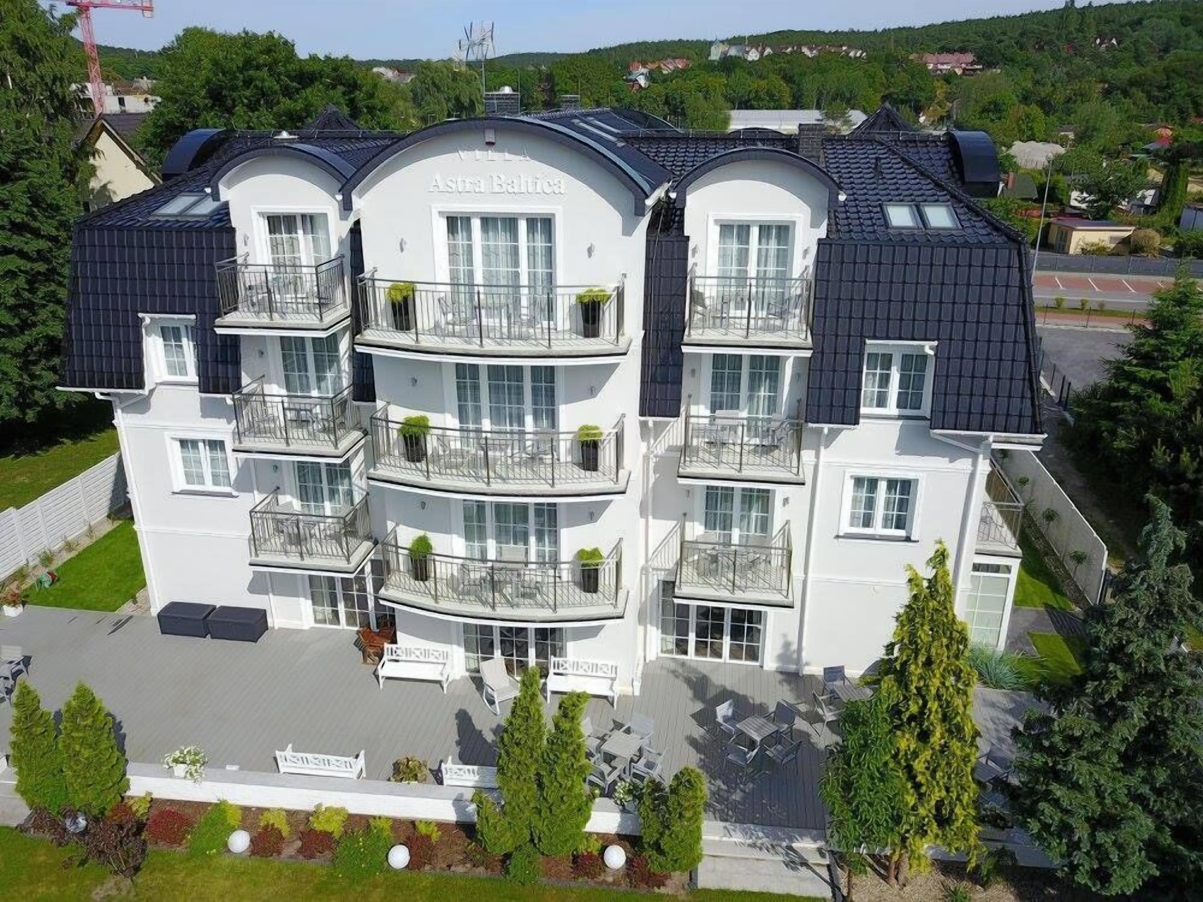 A multi-story hotel with balconies, a covered outdoor seating area, and a sign reading "Astra Baltica".