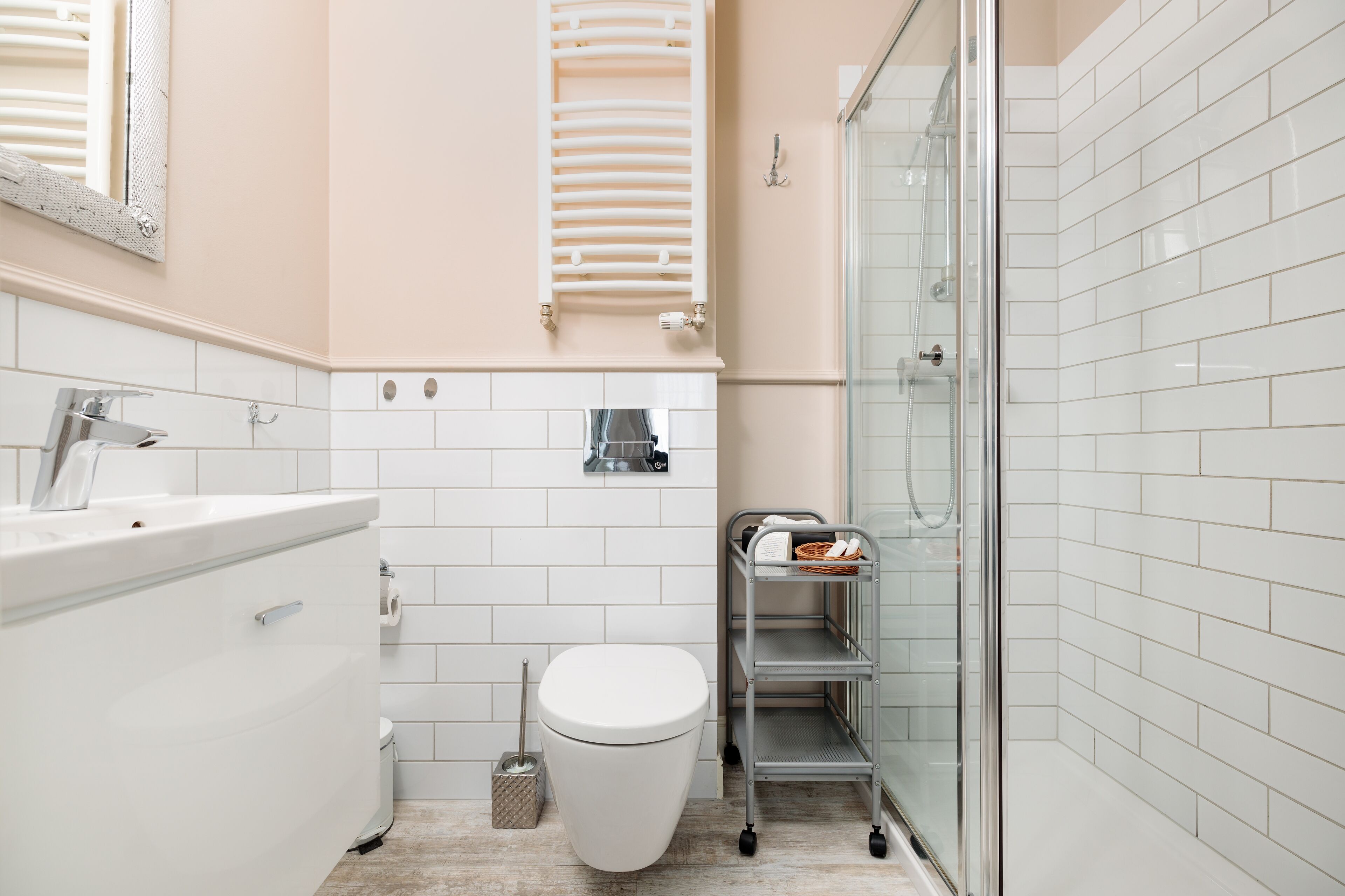 Une salle de bain moderne avec des toilettes blanches, un lavabo, une douche et un espace de douche séparé par des parois de verre.