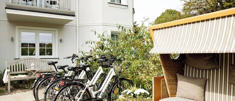 A building with a balcony, a bench, and bicycles parked outside.
