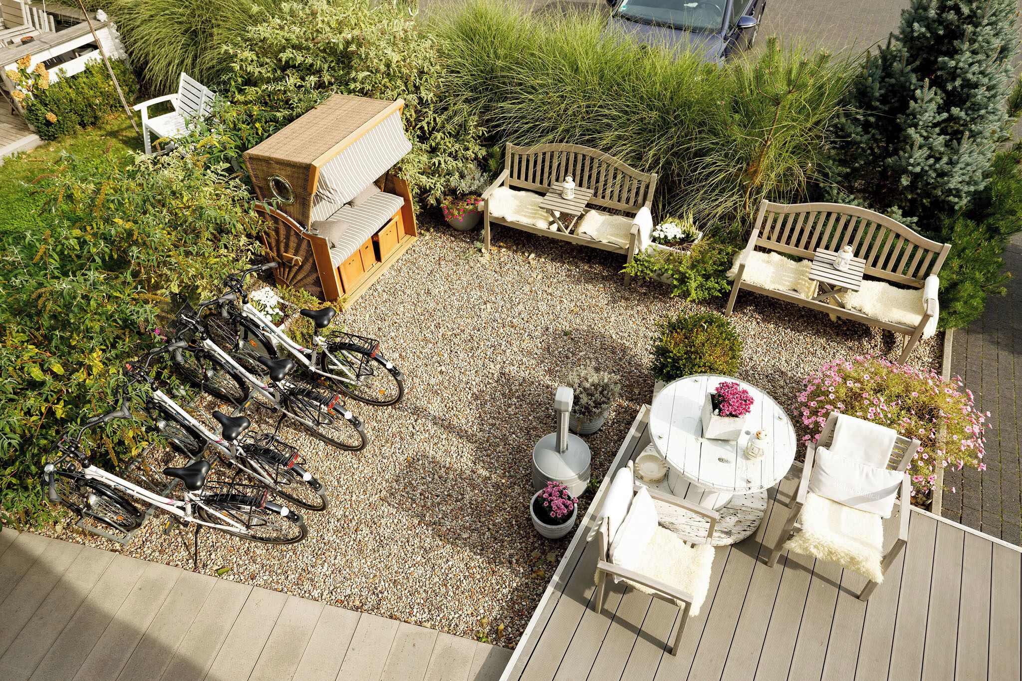 An outdoor patio area with a wooden bench, a round table with chairs, and a bicycle rack.