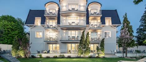 A multi-story hotel with balconies, outdoor seating, and a well-maintained lawn.