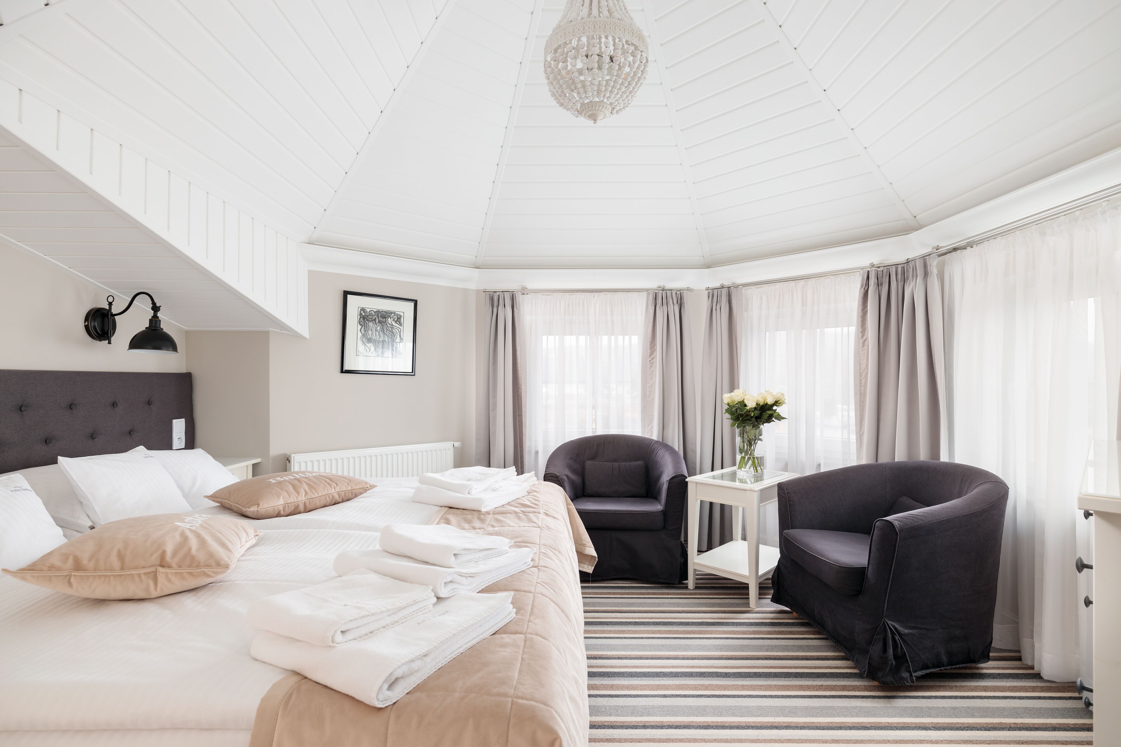Een hotelkamer met een bed, een stoel, een klein tafeltje en een kroonluchter.