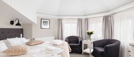 A hotel room with a bed, a chair, a small table, and a chandelier.