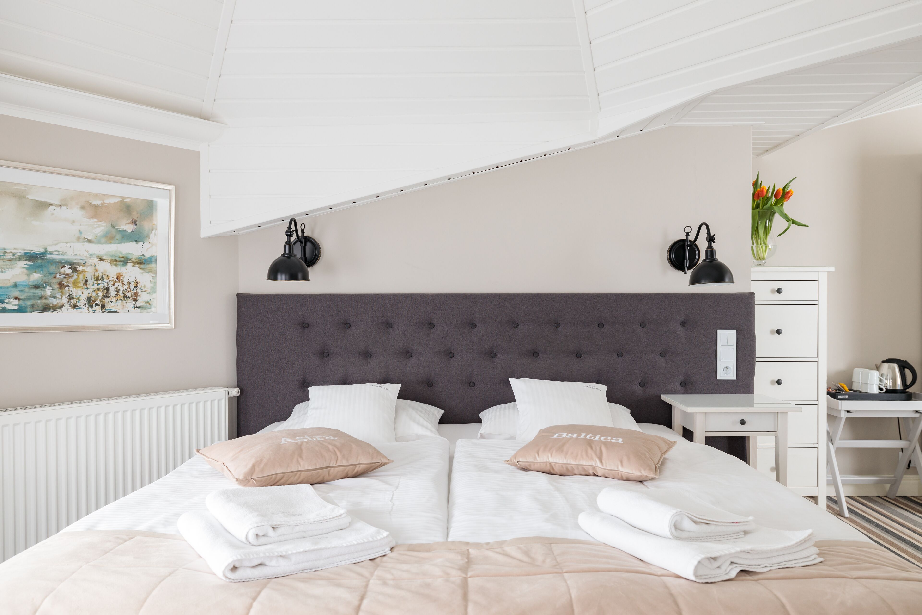 A double bed with a grey headboard, white bedding, and two beige pillows.