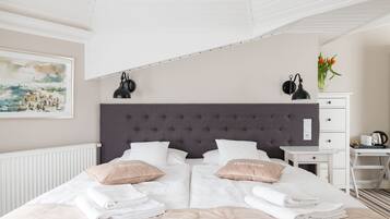 A double bed with a grey headboard, white bedding, and two beige pillows.