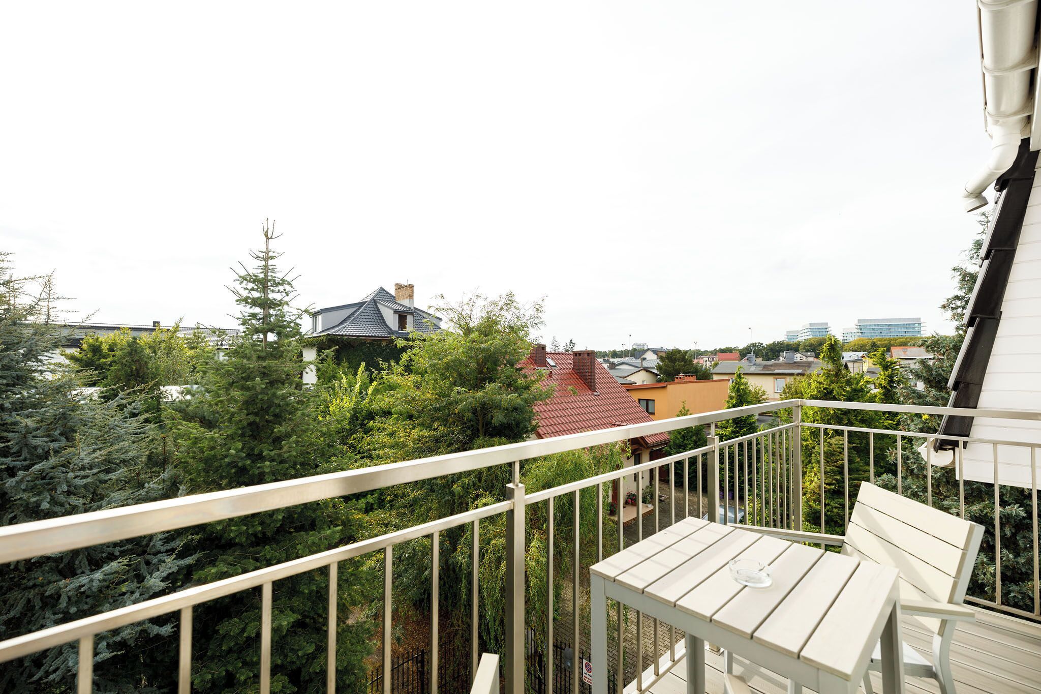 Ein Balkon mit weißer Brüstung, einem Holztisch und einer Bank.