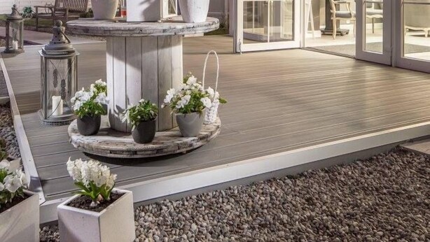 Un edificio moderno con un espacio exterior circular, plantas en macetas y una fuente central.