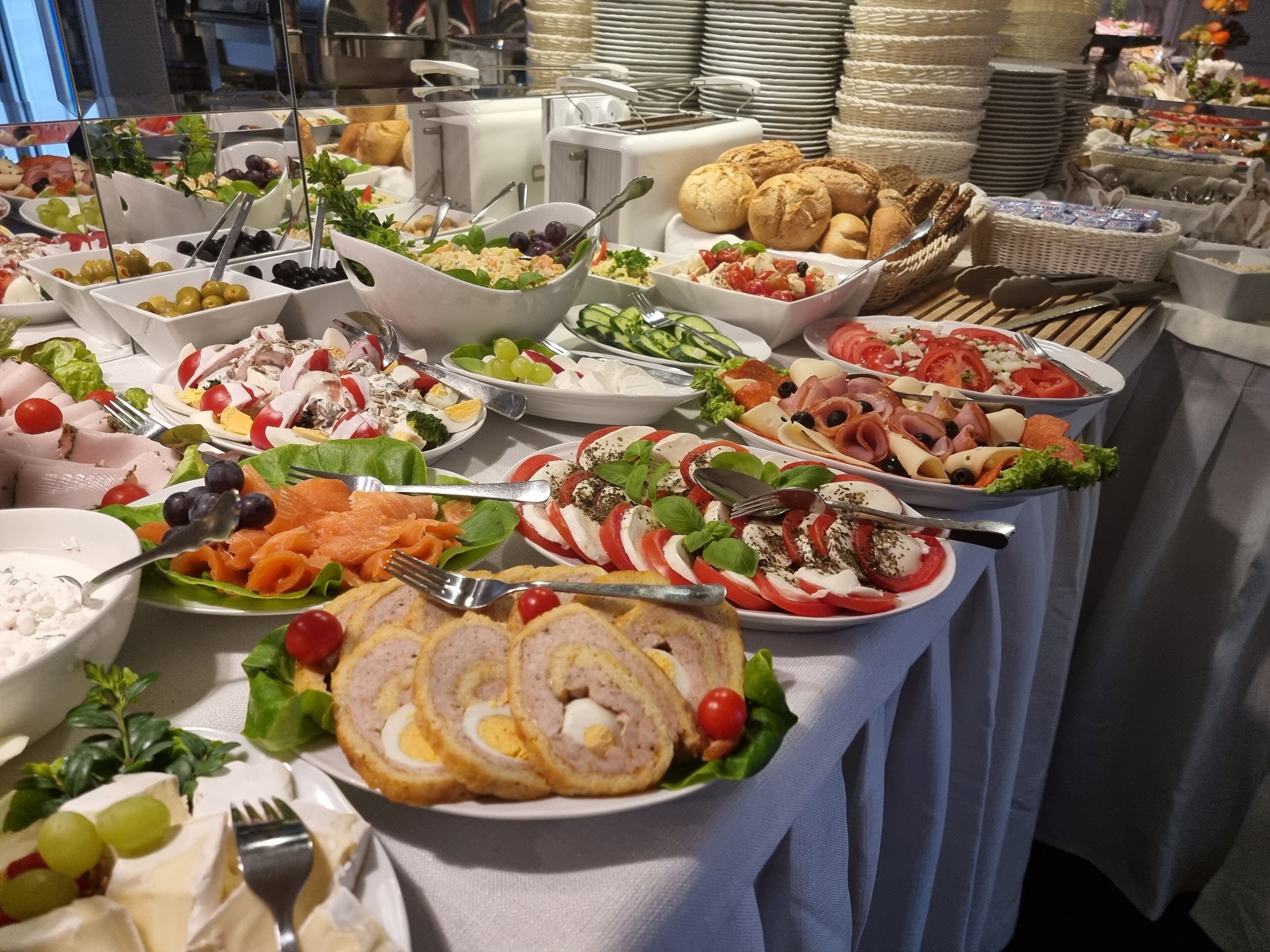 Un bufé con diversas opciones de comida, incluyendo ensaladas, carnes y quesos.
