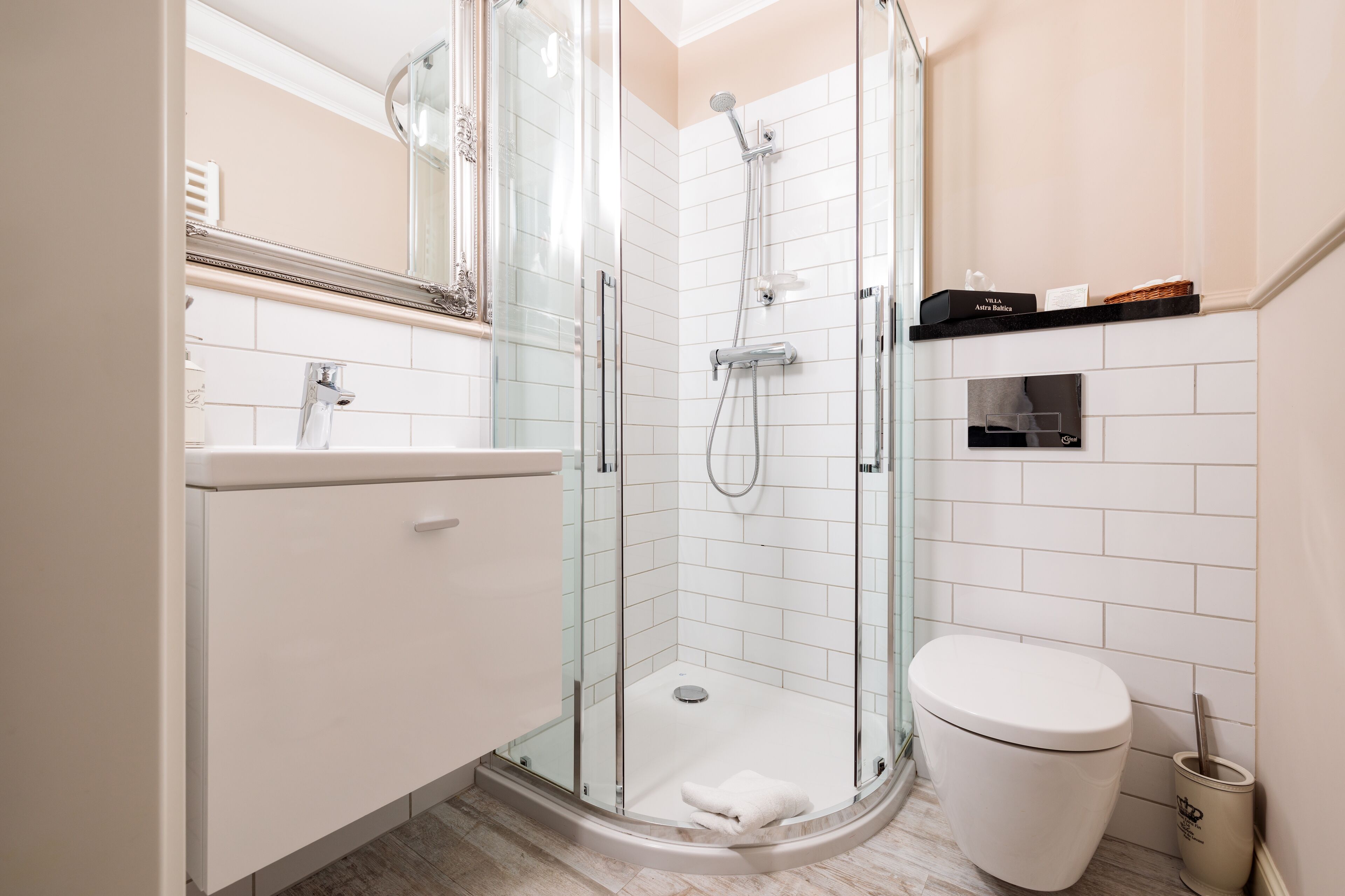 Un baño moderno con ducha de vidrio, inodoro blanco y tocador con espejo.