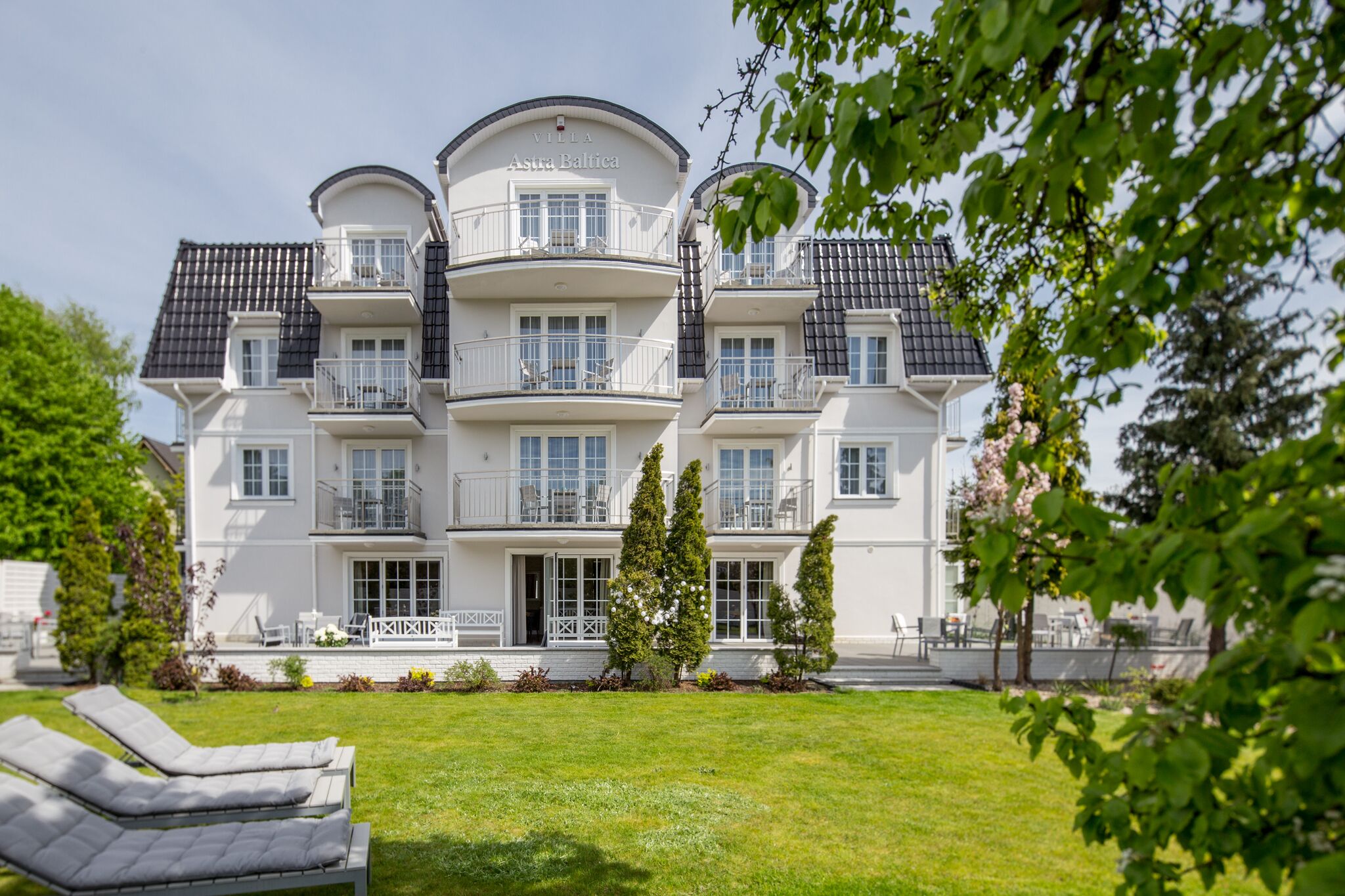 A multi-story hotel with balconies, a well-maintained lawn, and outdoor seating.