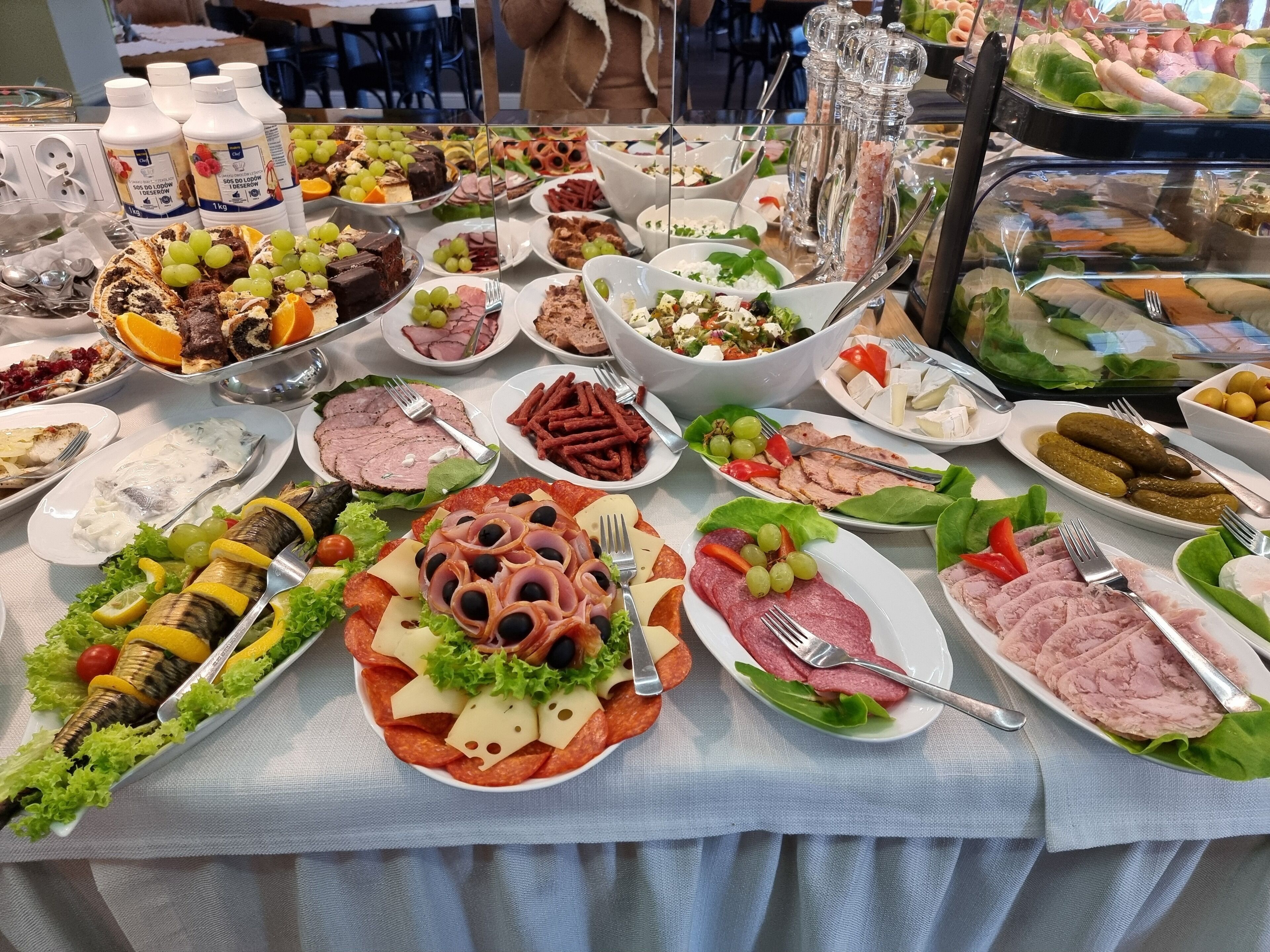 A buffet table with various food items including meats, cheeses, and salads.
