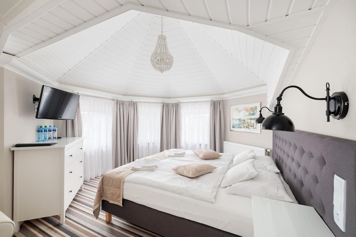 Un dormitorio con cama, escritorio, televisor y candelabro.