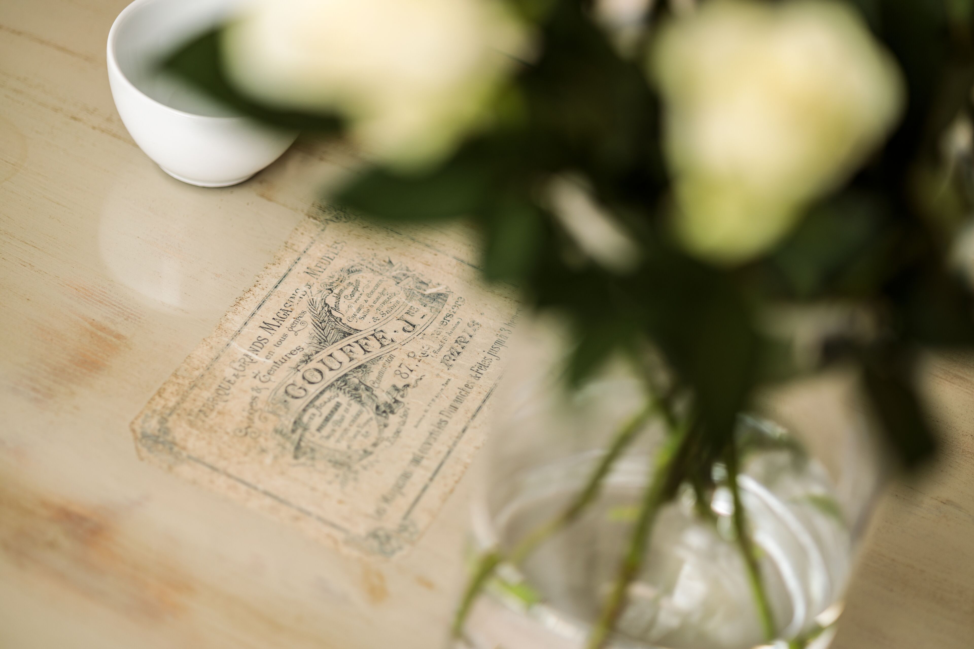 A vintage-style menu with text and a white cup on a wooden table.