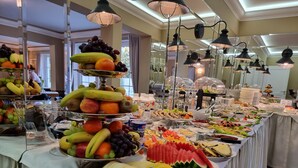 Un bufé con diversas frutas y platos, que incluye una exhibición de frutas y una variedad de opciones gastronómicas.