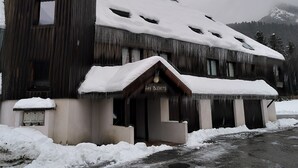 A rustic wooden building with a snow-covered roof and a sign reading "Les Bleuets."