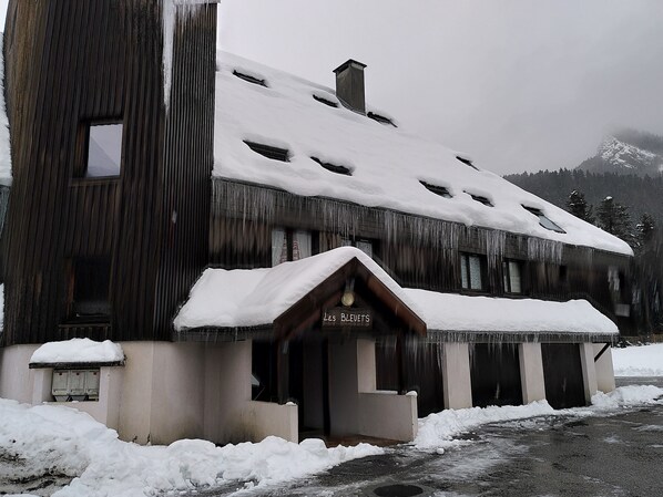 A rustic wooden building with a snow-covered roof and a sign reading "Les Bleuets."