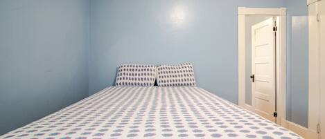 A bedroom with a bed, two pillows, and a door.