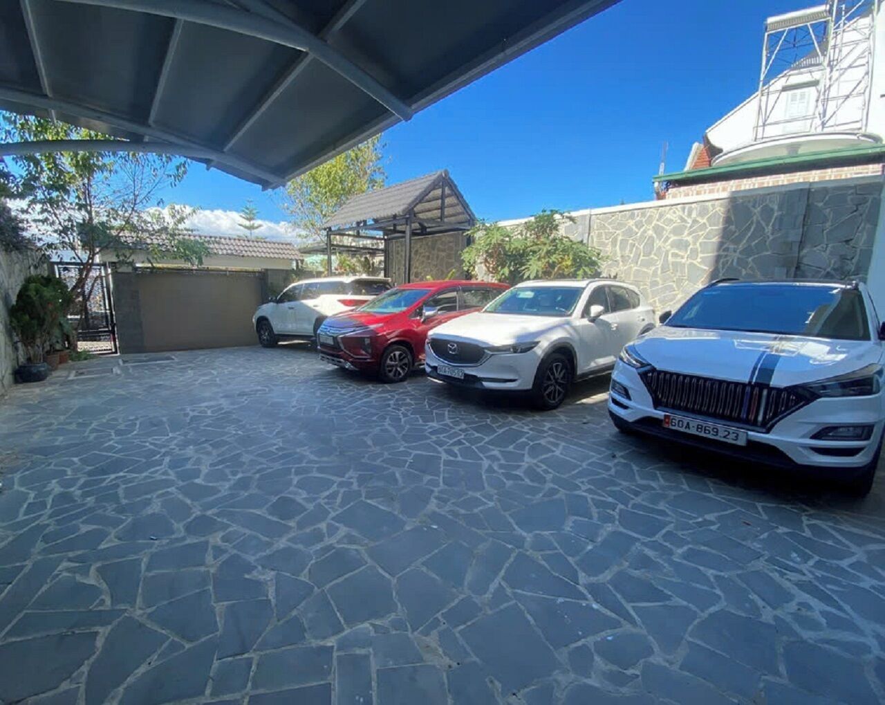 A covered parking area with four cars parked in a row.