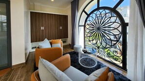 A modern living room with a large window, a sofa set, a wooden wardrobe, and a decorative metal gate. - KSol Hotel & Apartment (Cam Ly - Da Lat)