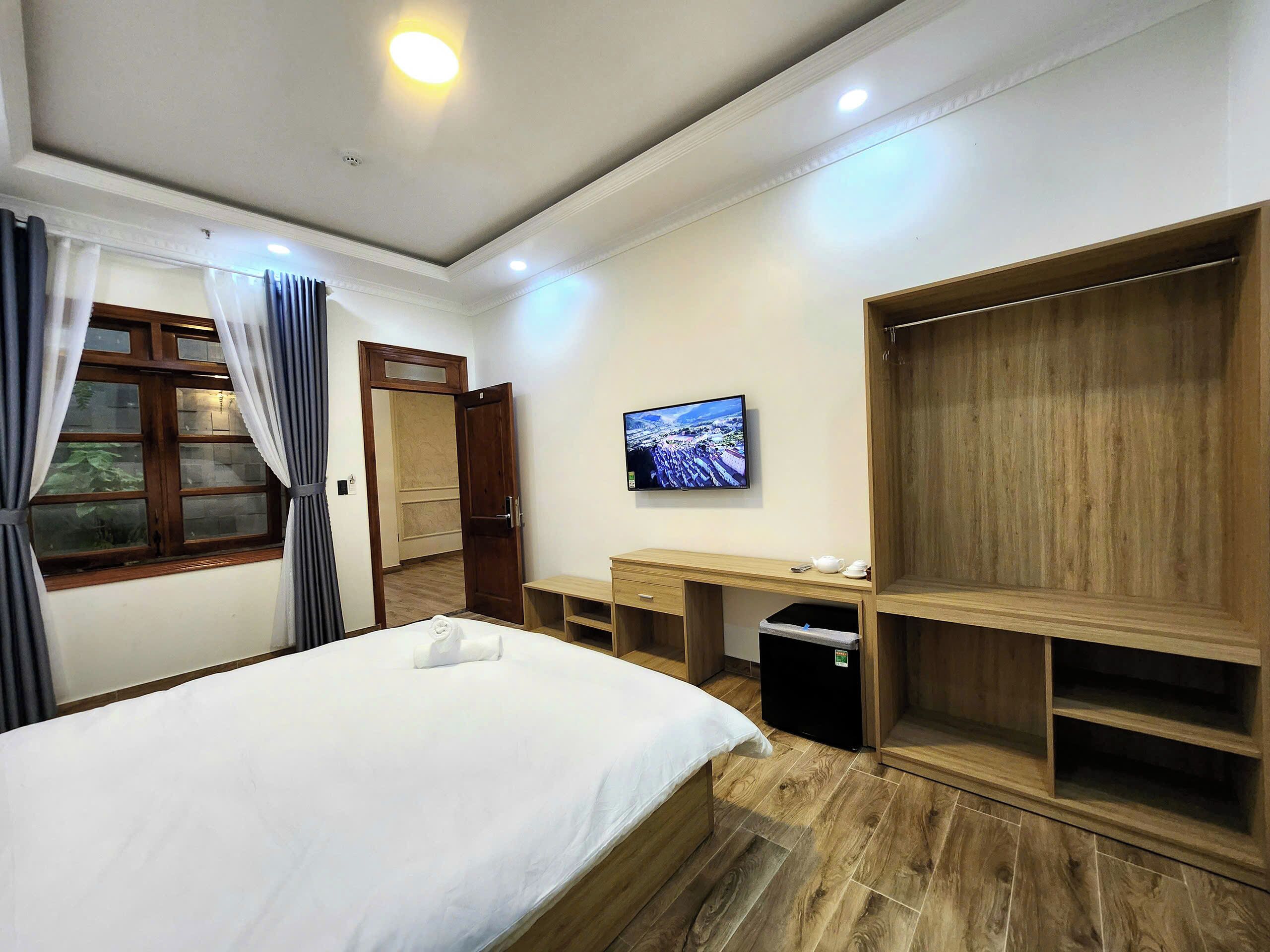 Una habitación de hotel con cama, escritorio, televisor y armario.
