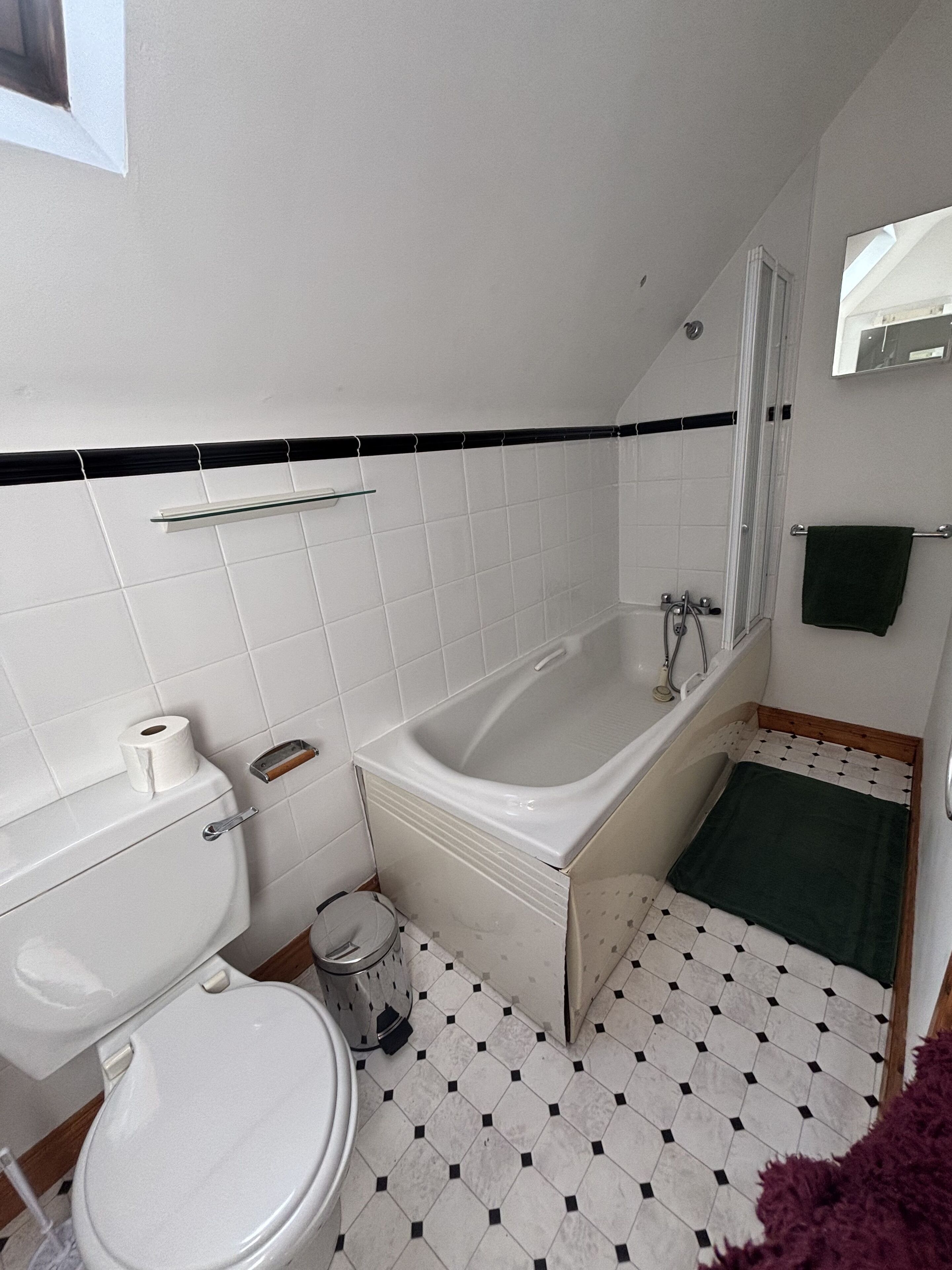 A bathroom with a toilet, sink, bathtub, and a small window.
