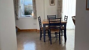 A dining area with a table and chairs, a window with curtains, and a picture on the wall.