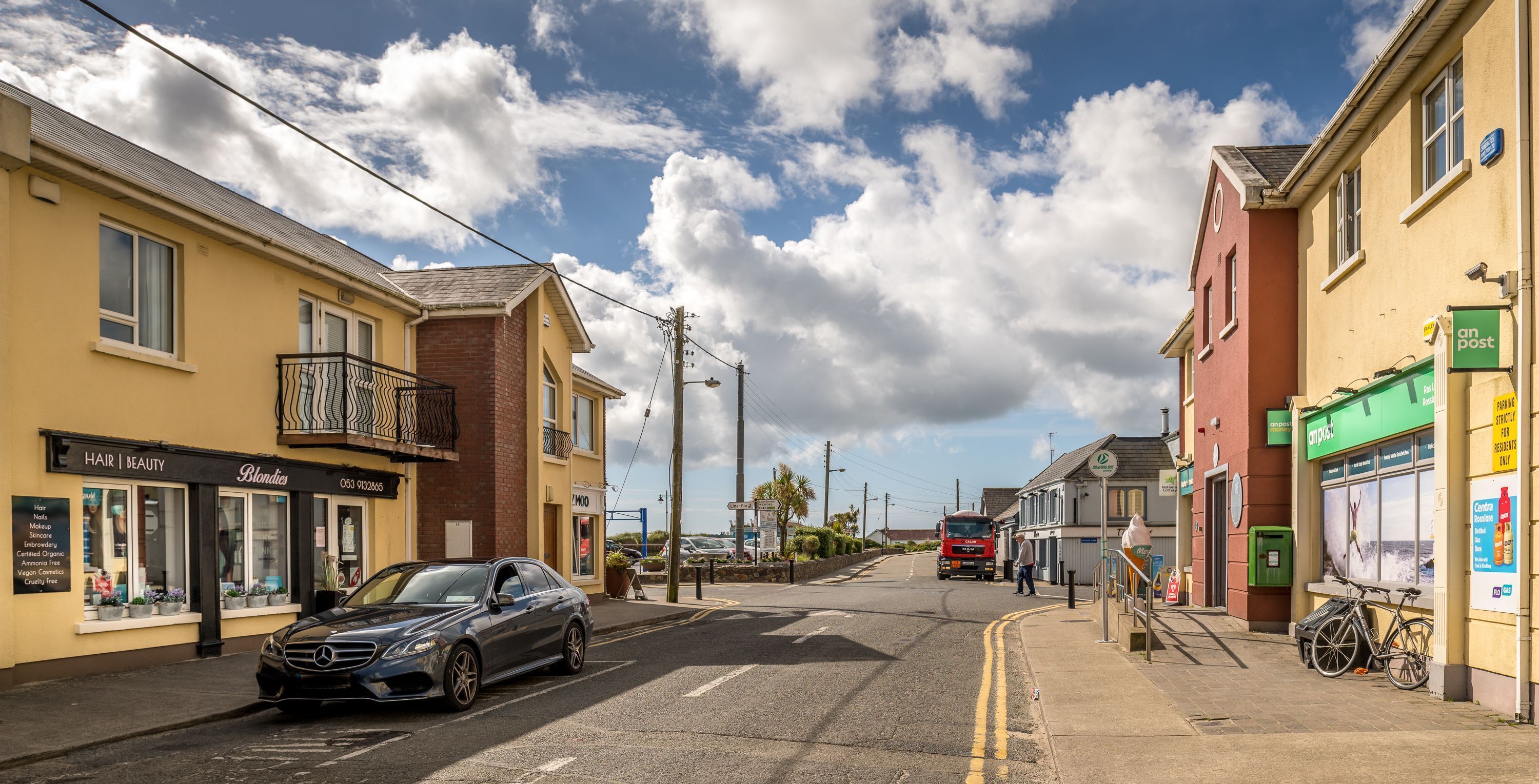 A street view with a salon, a red truck, and a bicycle.