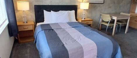 A hotel room with a bed, two bedside tables, a desk, and a chair.