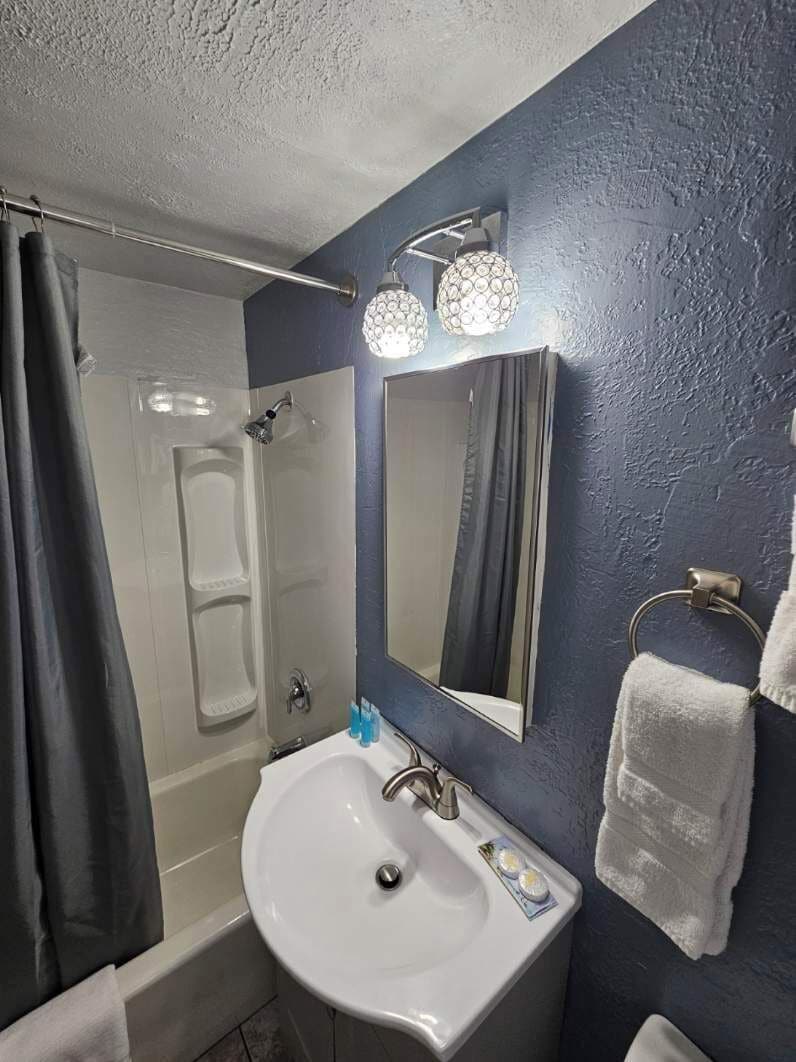 A bathroom with a bathtub, a sink, a mirror, and a towel rack.