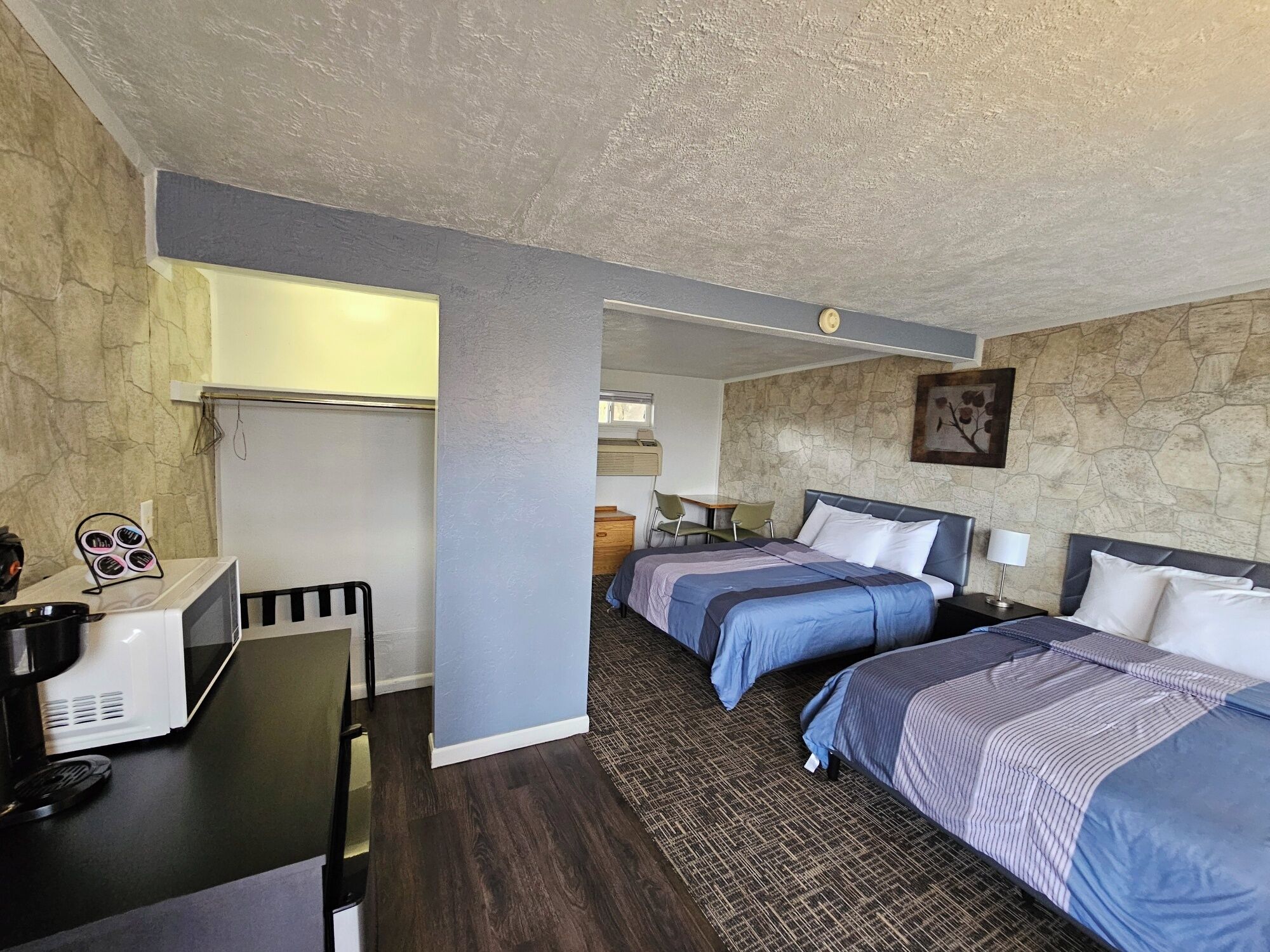 A hotel room with two beds, a desk with a computer, a chair, and a small table.