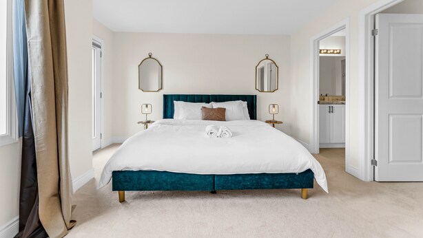 A spacious bedroom with a large bed, two bedside tables, and a mirror above the bed.