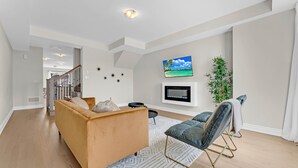 A modern living room with a sofa, a chair, a TV, and a plant.