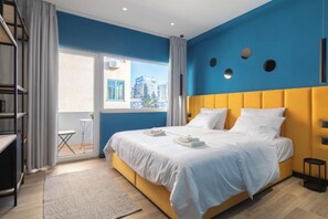 Een moderne hotelkamer met een groot bed, een balkon met uitzicht op gebouwen, en een stadsgezicht.