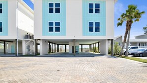 A modern building with a light blue and white facade, multiple windows, and a paved entrance area. - Premier Retreat: Pool & Steps from Waterville (Gulf Shores)