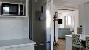 A modern kitchen with a stainless steel refrigerator, a microwave, and a dining area with a table and chairs. - Spacious cocoon in Six-Fours-les-Plages (Six-Fours-les-Plages)