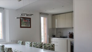 A modern kitchen with white cabinets, a central island with chairs, and a dining area with striped chairs. - Spacious cocoon in Six-Fours-les-Plages (Six-Fours-les-Plages)