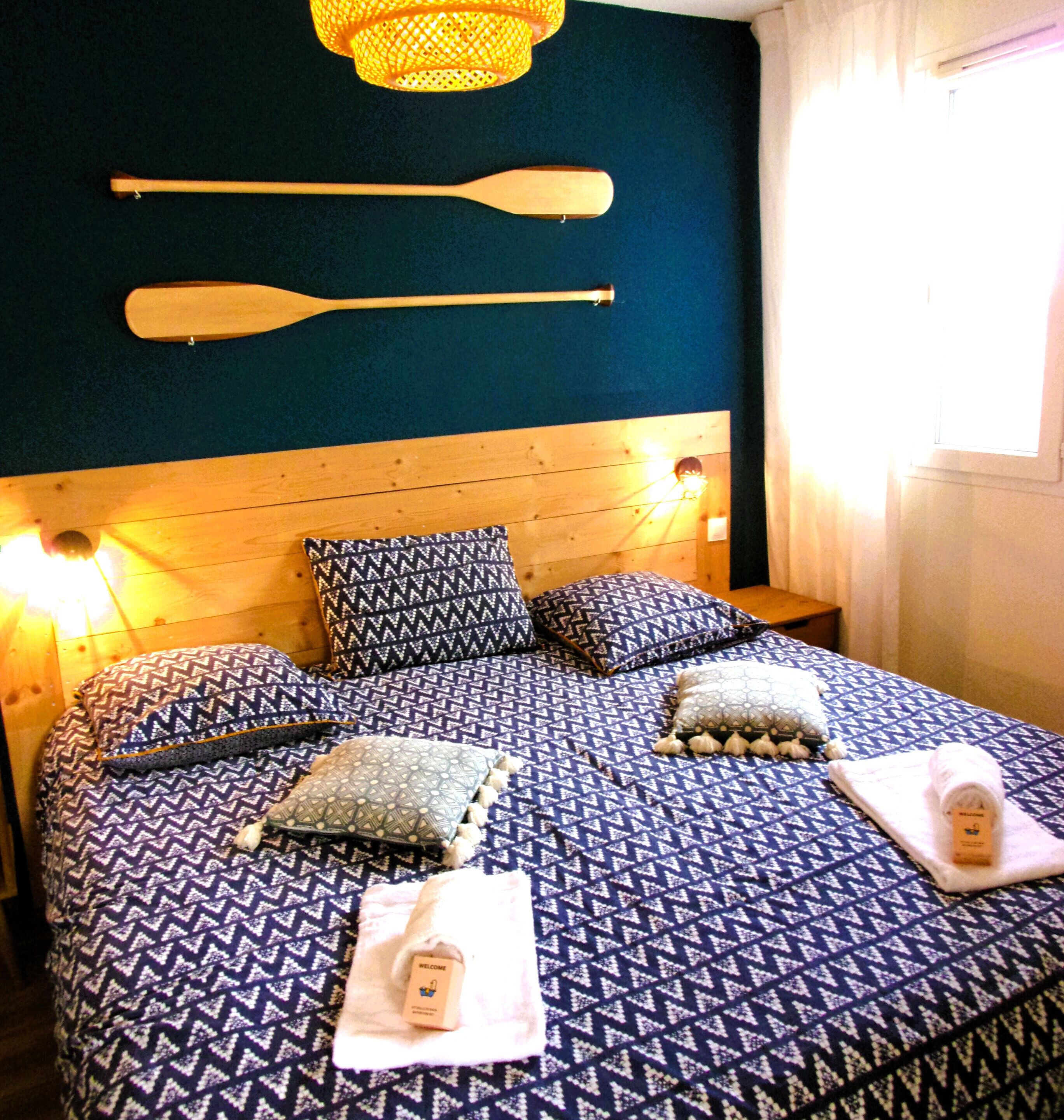 Un lit avec une couvre-lit à motifs, des oreillers et une carte de bienvenue.