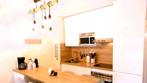 A modern kitchen with a wooden table, four chairs, a coffee maker, and a knife block. - Comfortable apartment with pool (Moliets-et-Maa)