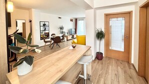 Ett modernt vardagsrum med ett matbord i trä, en gul soffa och en krukväxt.